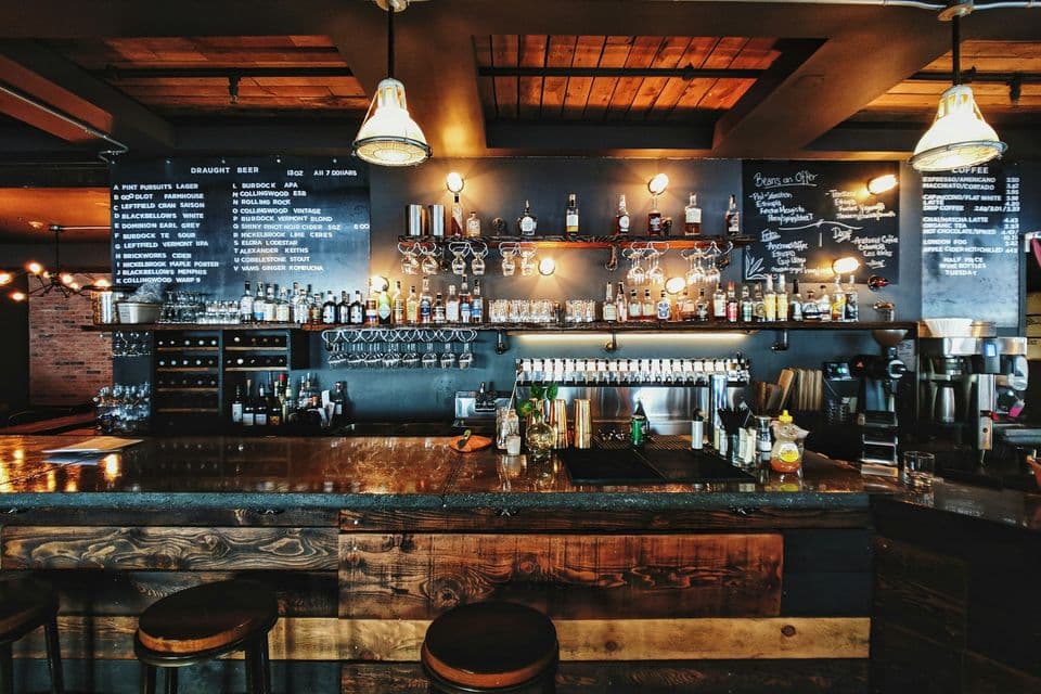 Bar d’hôtel avec tabourets et étagères de bouteilles